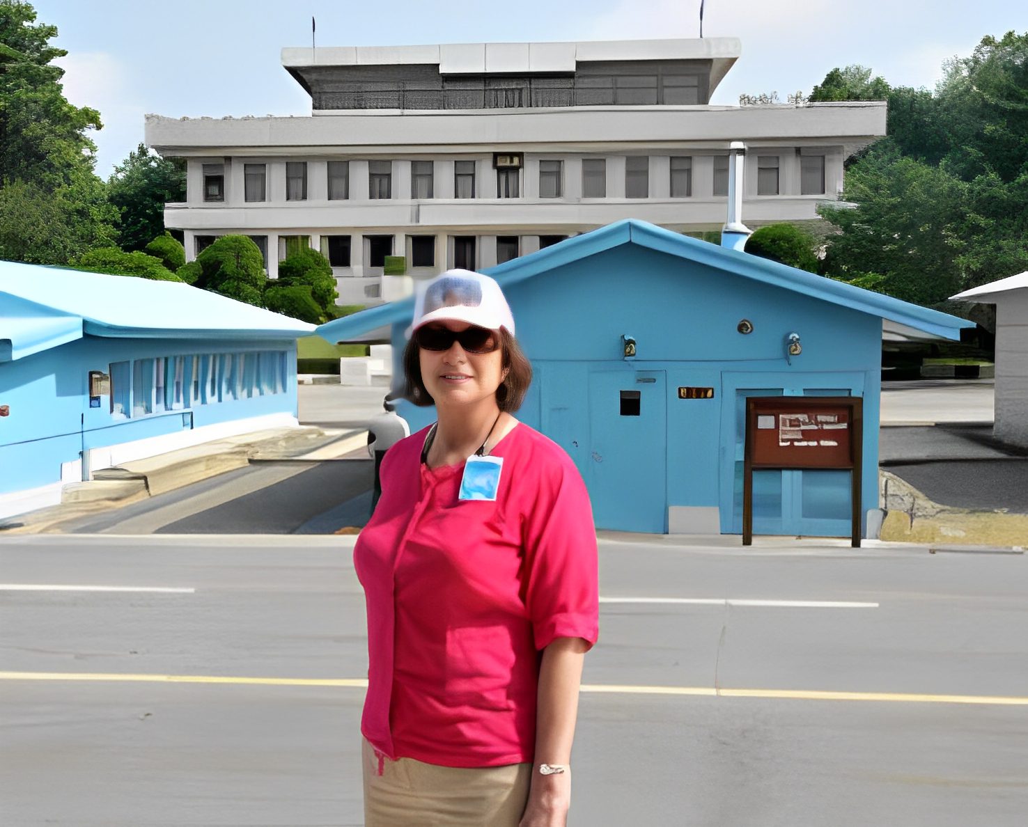 Woman standing near blue buildings, smiling.
