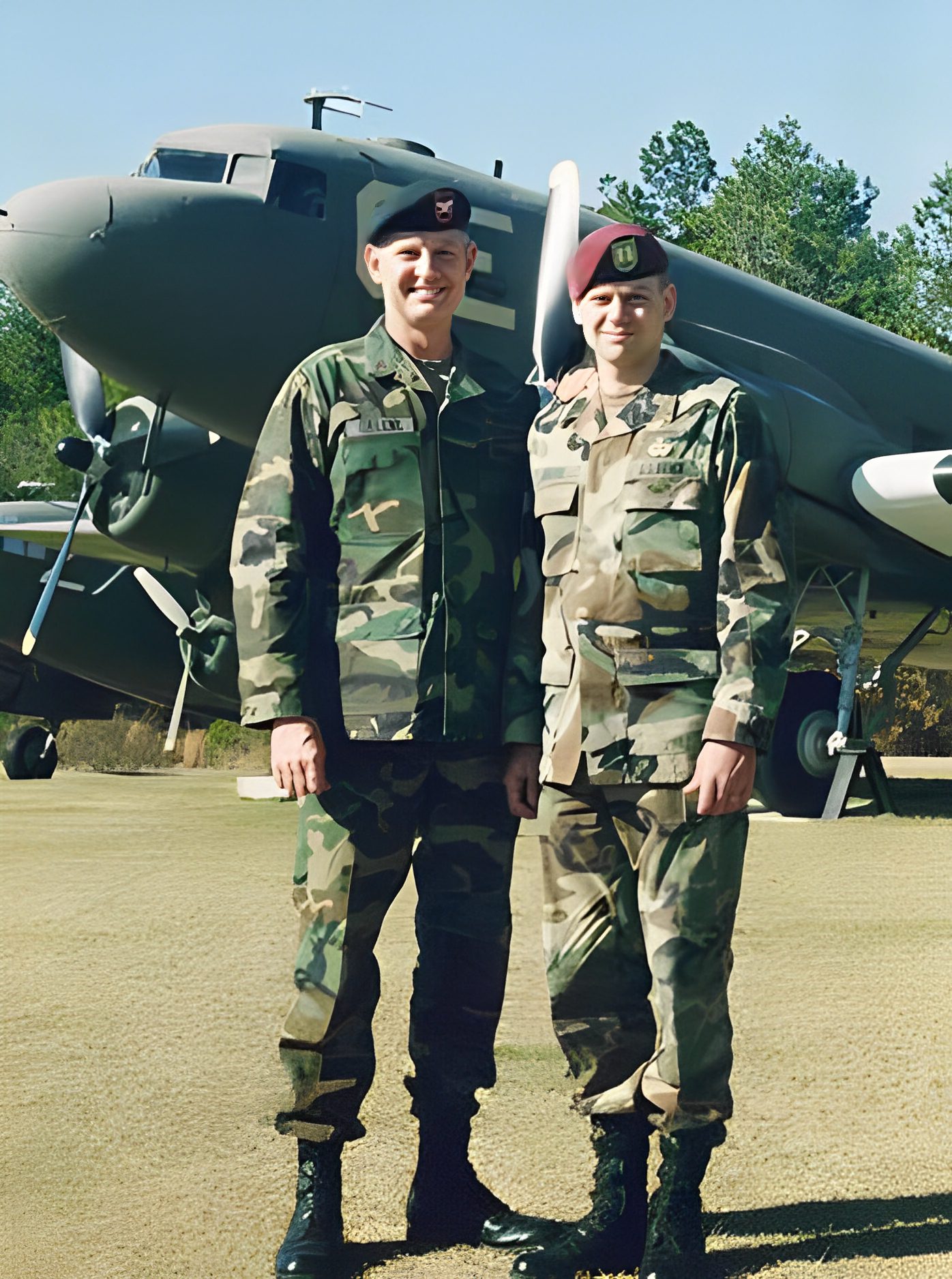 Two soldiers standing in front of airplane.