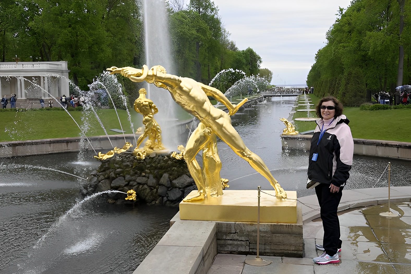 Person beside golden statue and fountain.