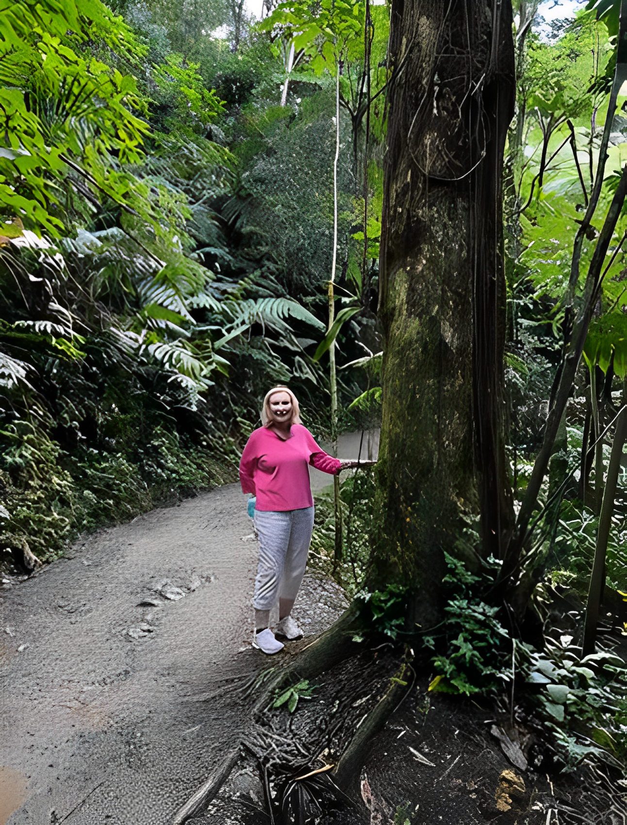 Person standing on forest path, smiling.