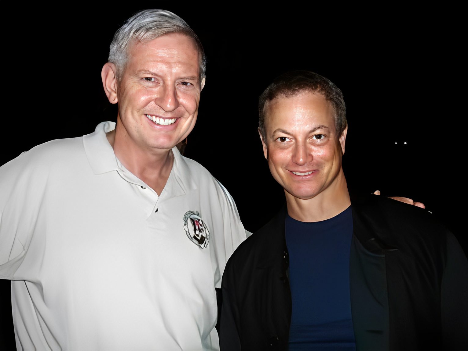 Two men smiling in a nighttime setting.