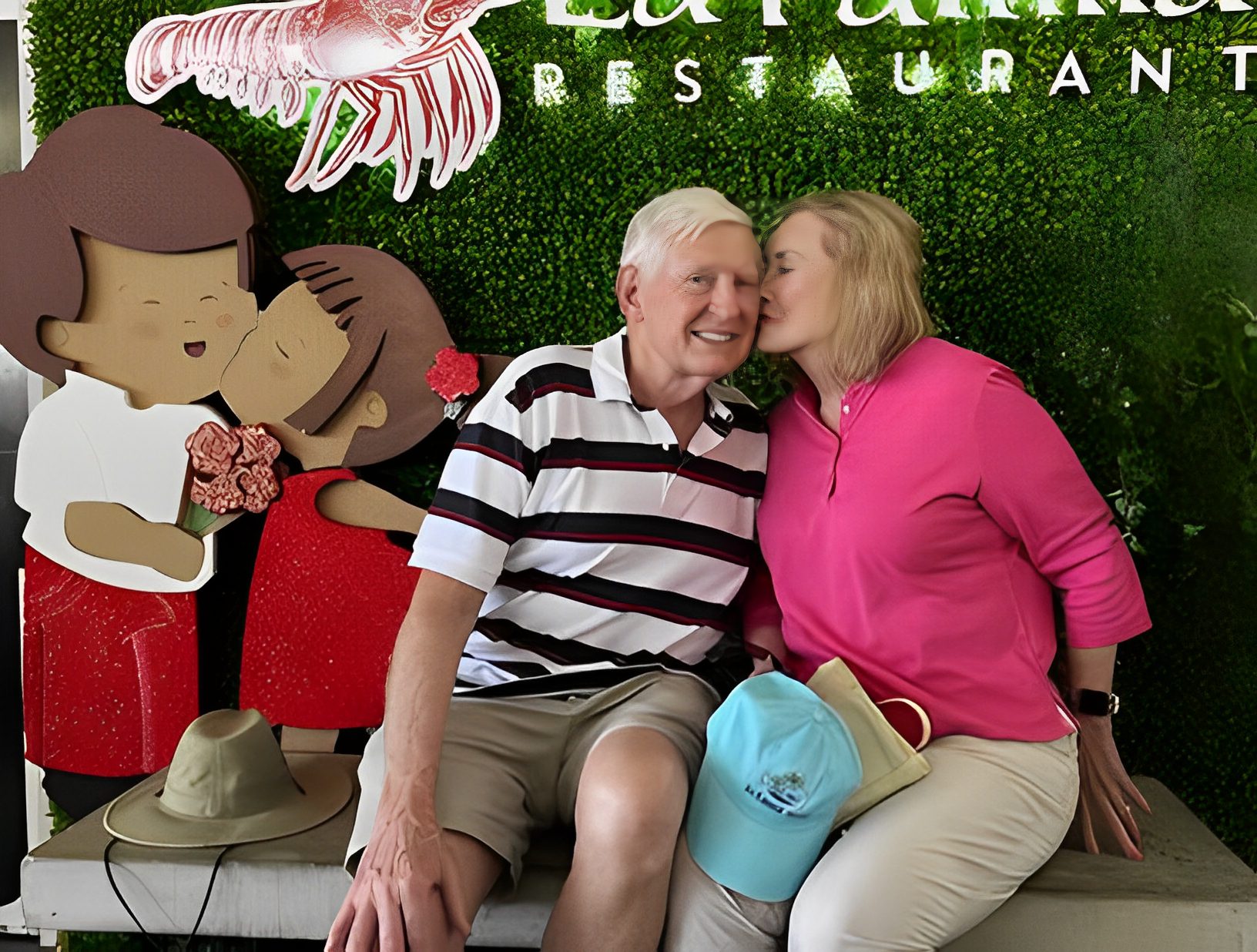 Couple sitting by restaurant sign display.