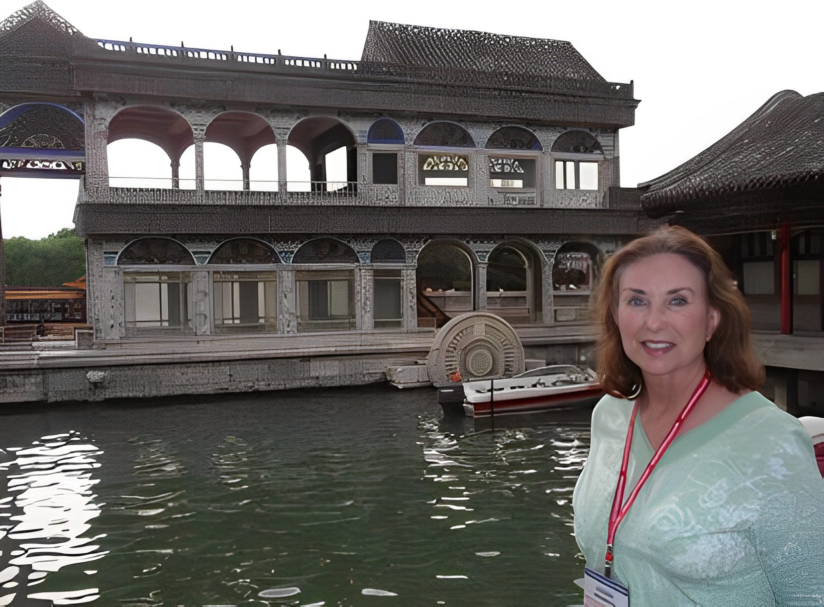 Woman standing near historic Chinese building, water.