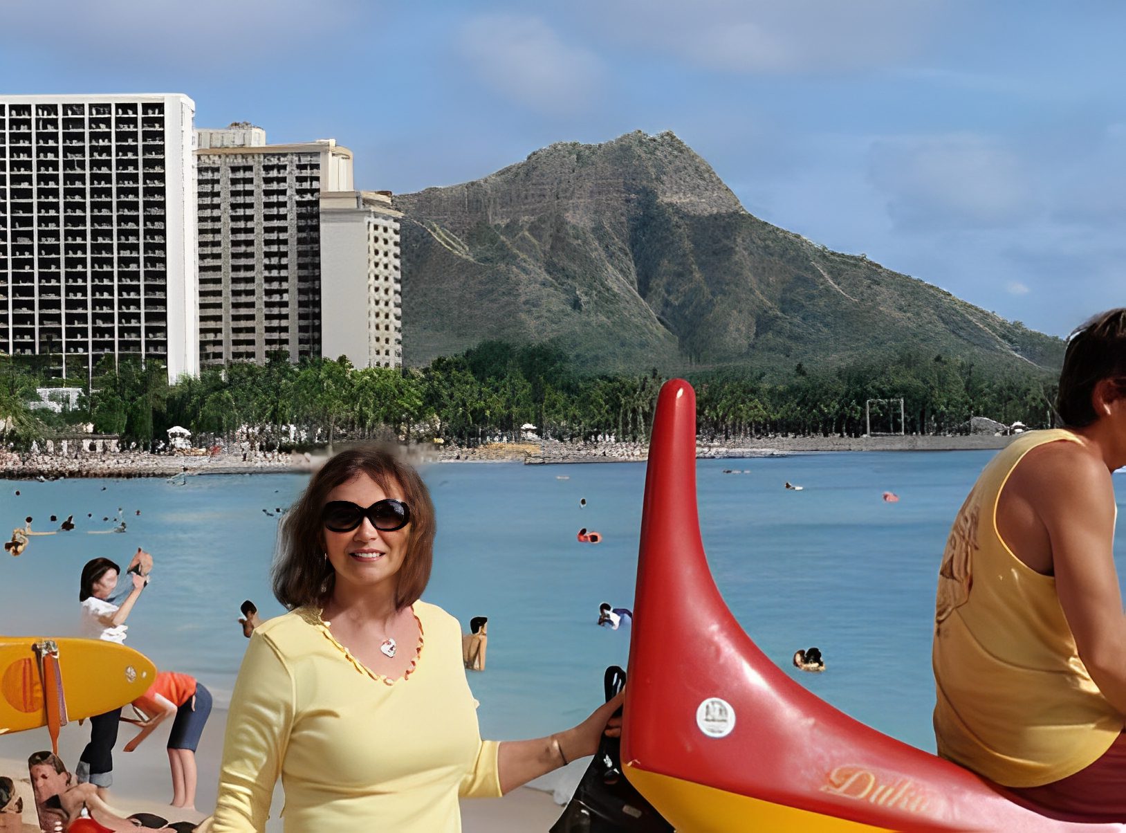 Woman smiling at beach with mountain backdrop.