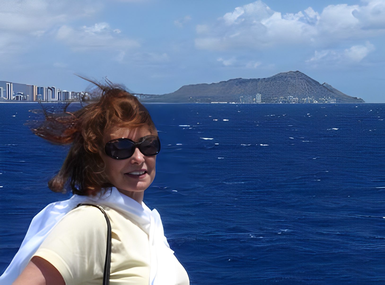 Woman on boat with ocean and island backdrop.