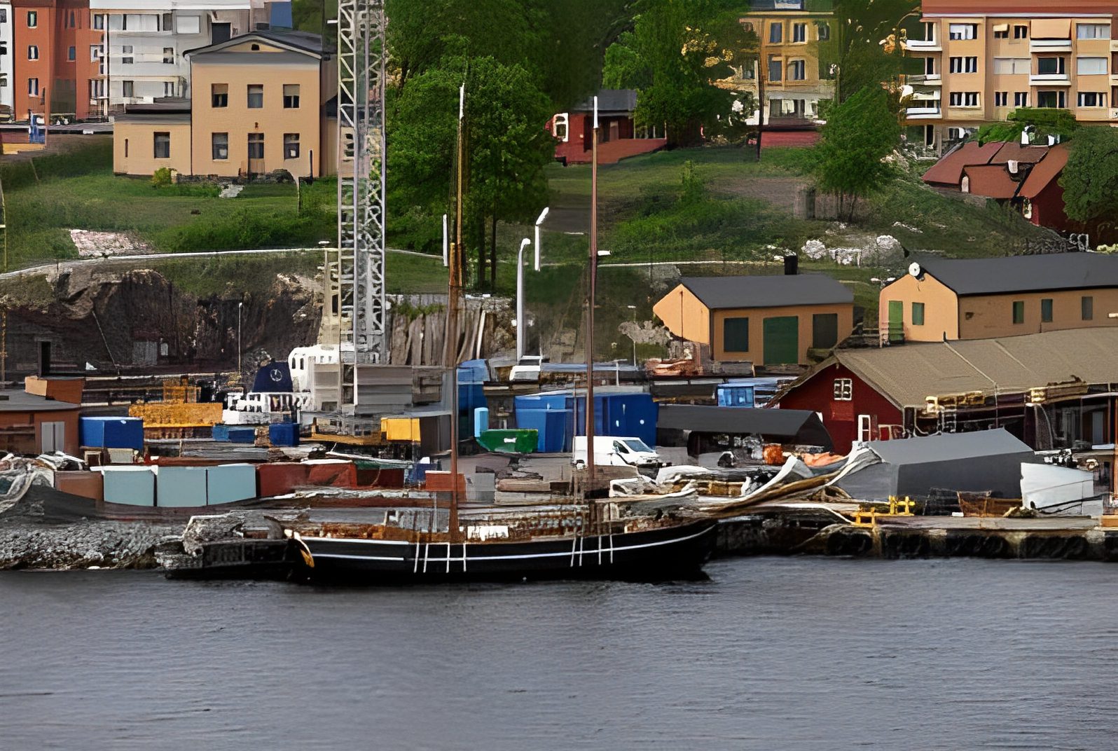 Sailboat docked near colorful town buildings.