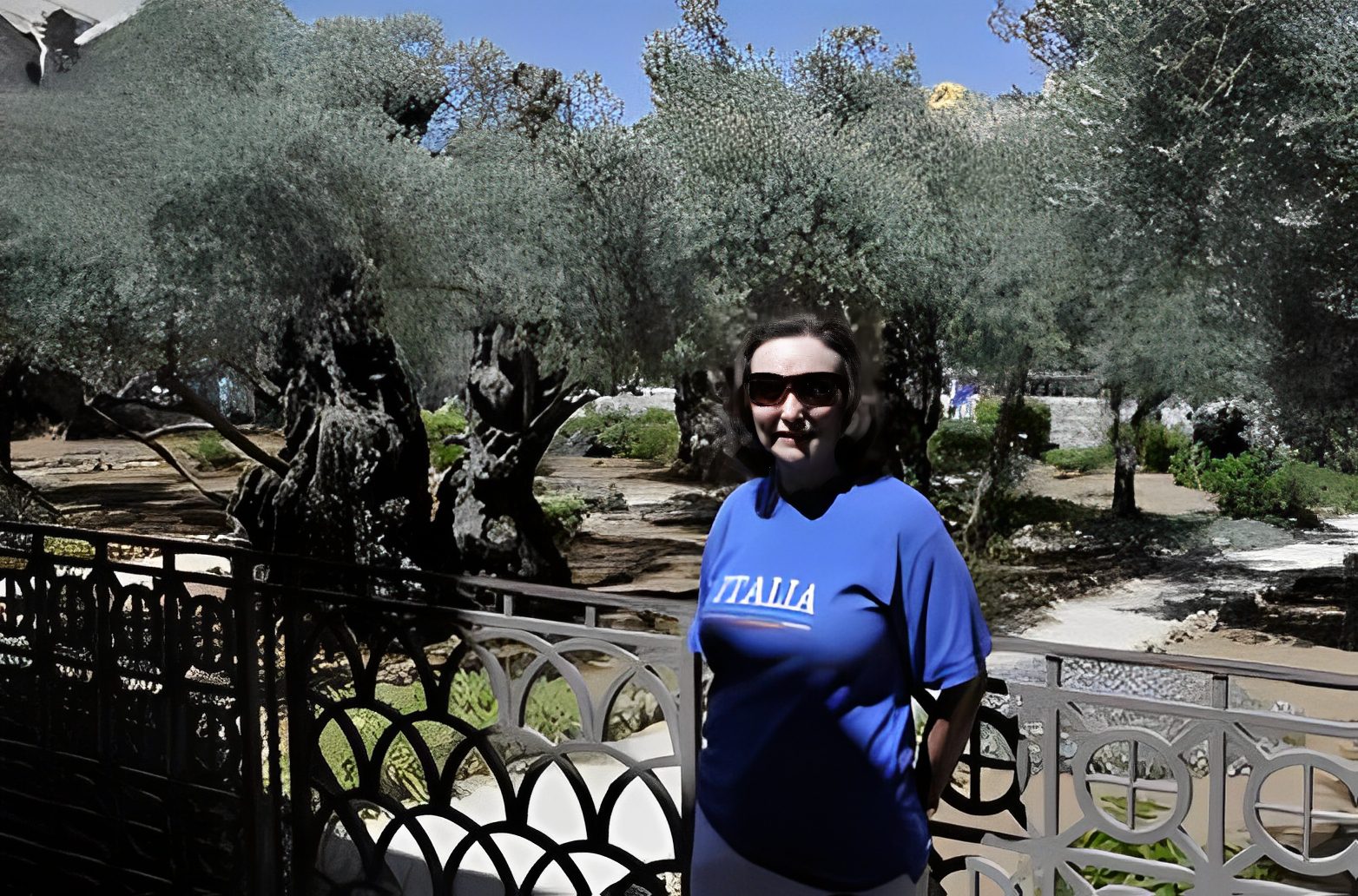 Person in blue shirt near lush trees.