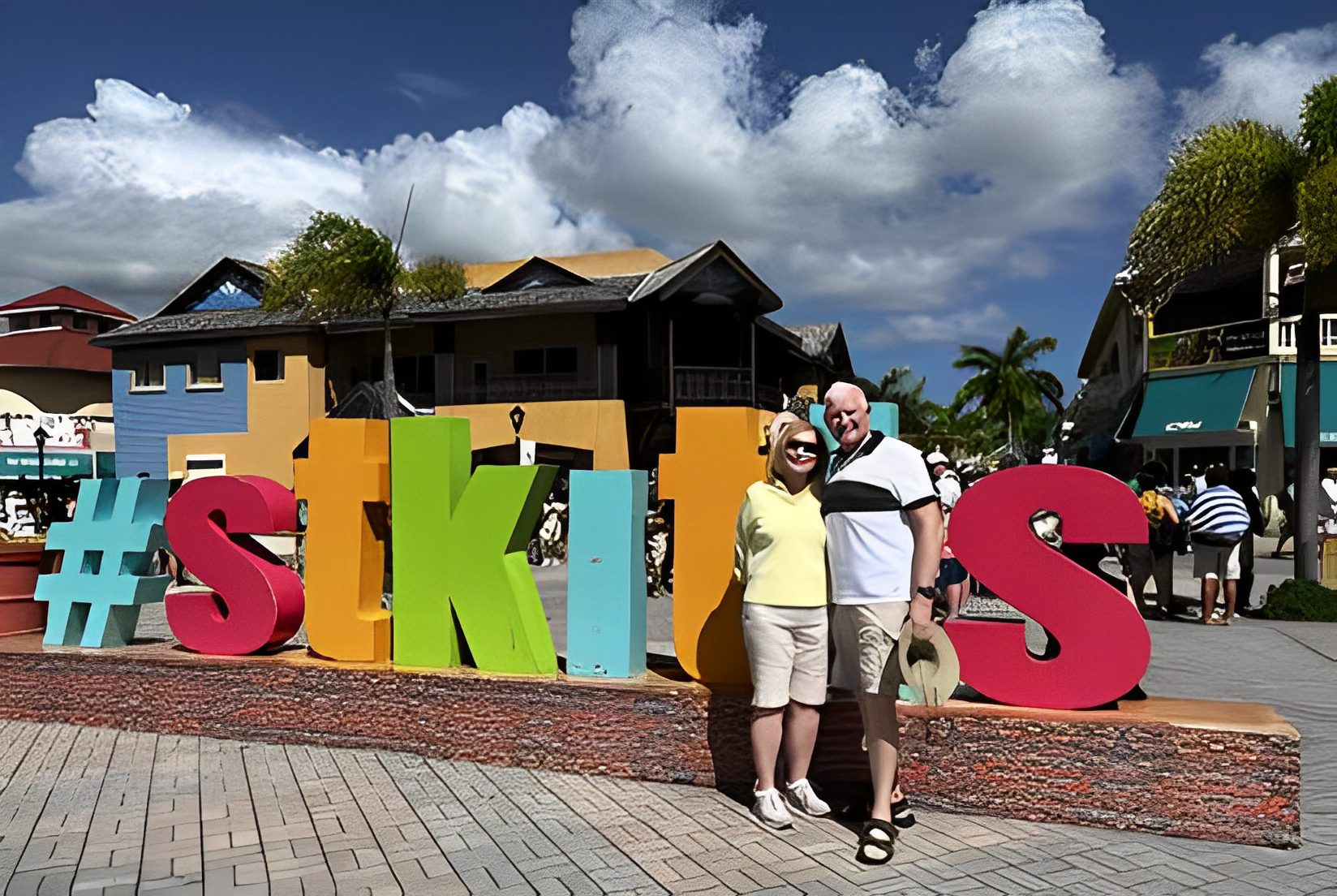 Couple posing by colorful St. Kitts sign.