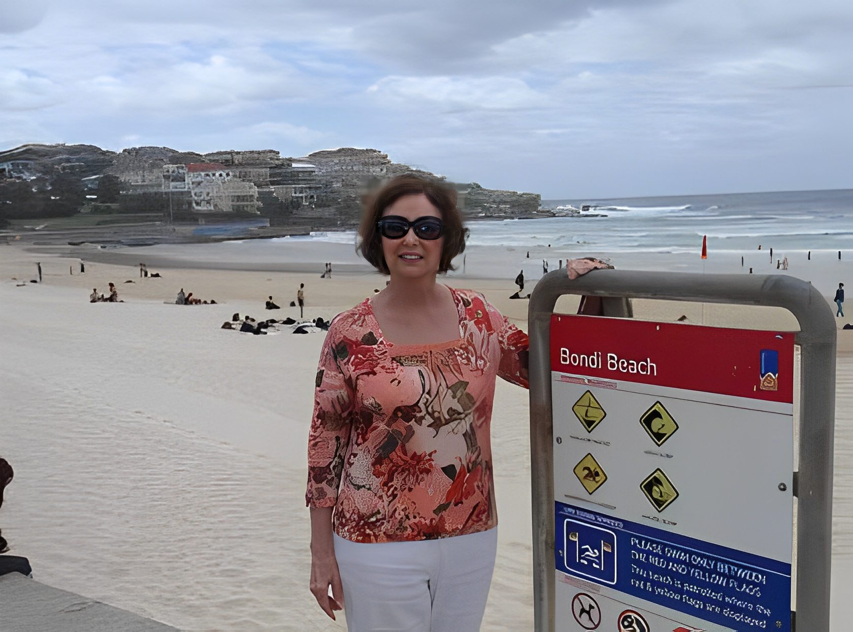 Woman smiling at Bondi Beach sign.
