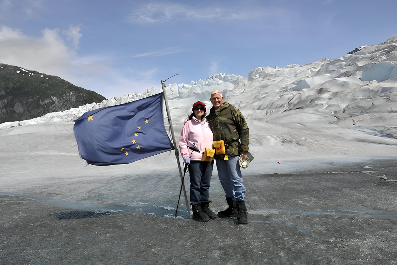 Couple with Alaska flag on glacier.