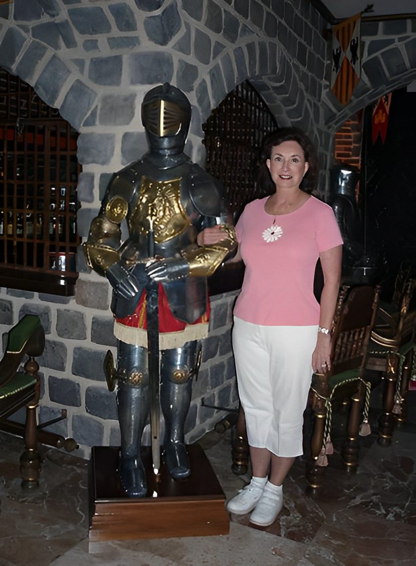 Woman standing beside a suit of armor.