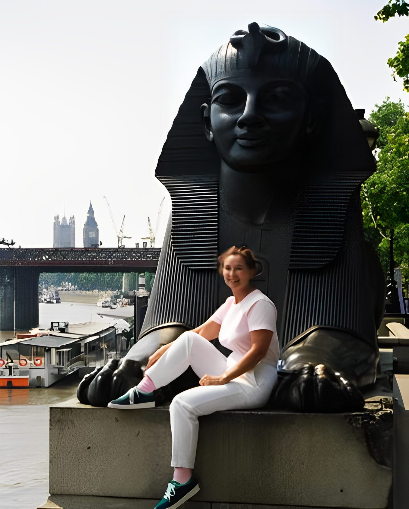Person sitting by large Egyptian-style statue.