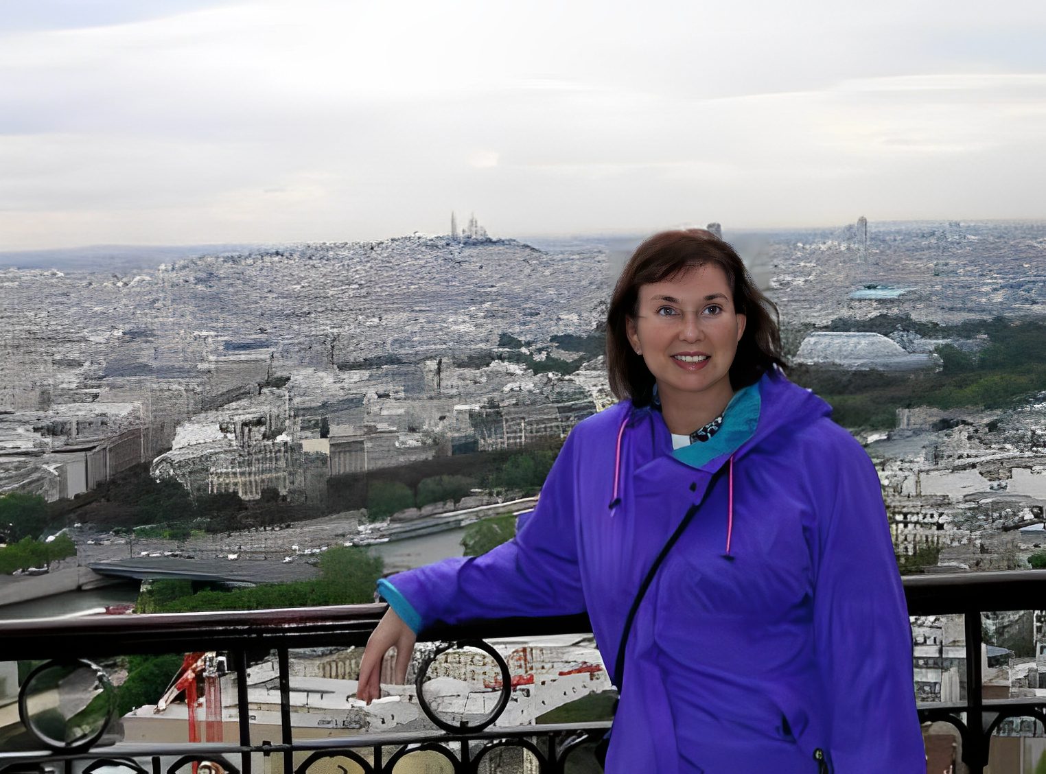 Woman on balcony overlooking Paris cityscape.