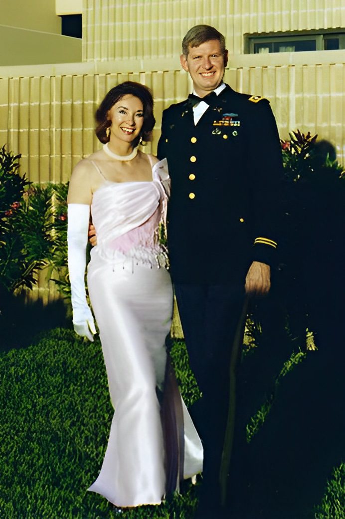 Couple dressed formally, standing on grass.