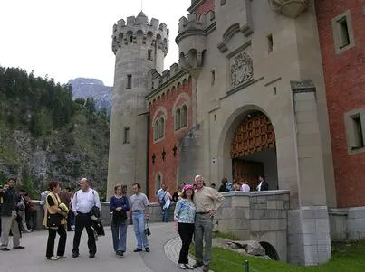 Tourists outside a historic stone castle entrance.