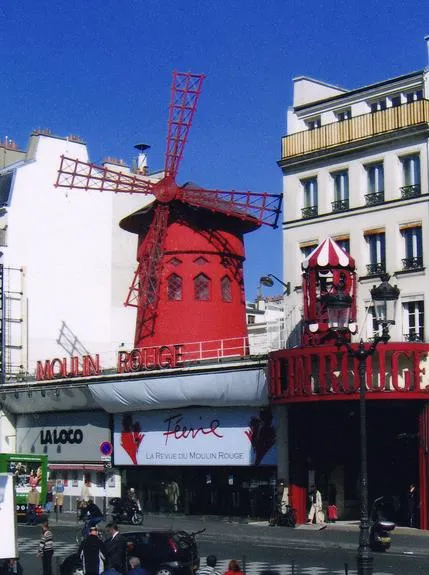 Red windmill on Moulin Rouge building facade.