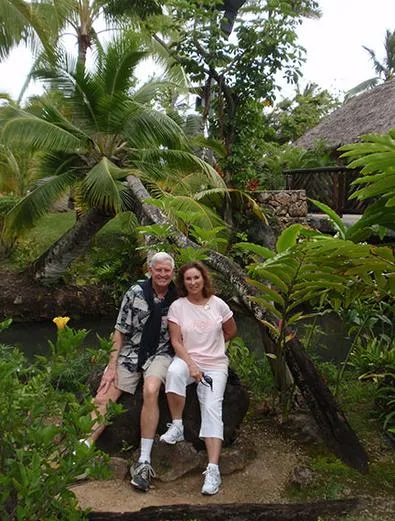 Couple sitting in tropical garden, smiling together.