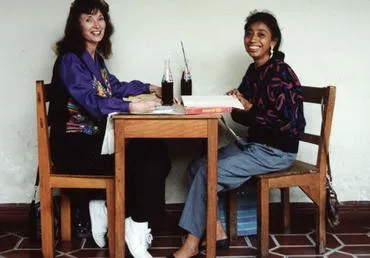 Two women sitting at a table, smiling.