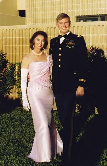 Couple posing in formal attire outside building.
