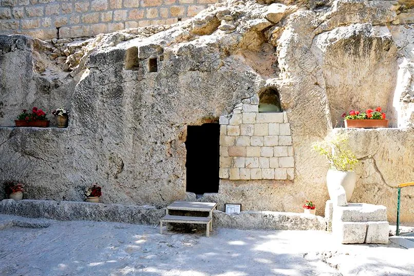 Stone tomb with plants and small entrance.