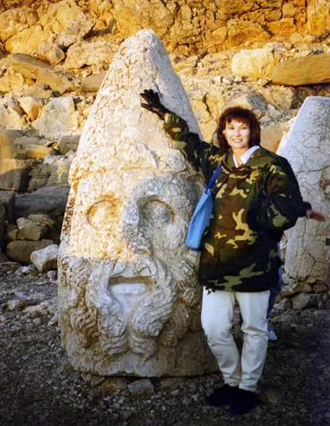Person posing with ancient stone head statue.