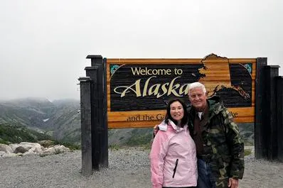 Couple posing at Alaska welcome sign.