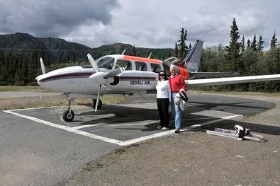 Two people standing near small airplane.