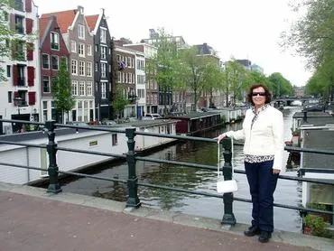 Woman standing by canal with buildings.