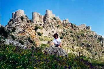 Person sitting near ancient stone castle ruins.