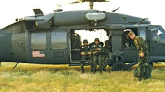 Soldiers sitting in military helicopter, grassy field.