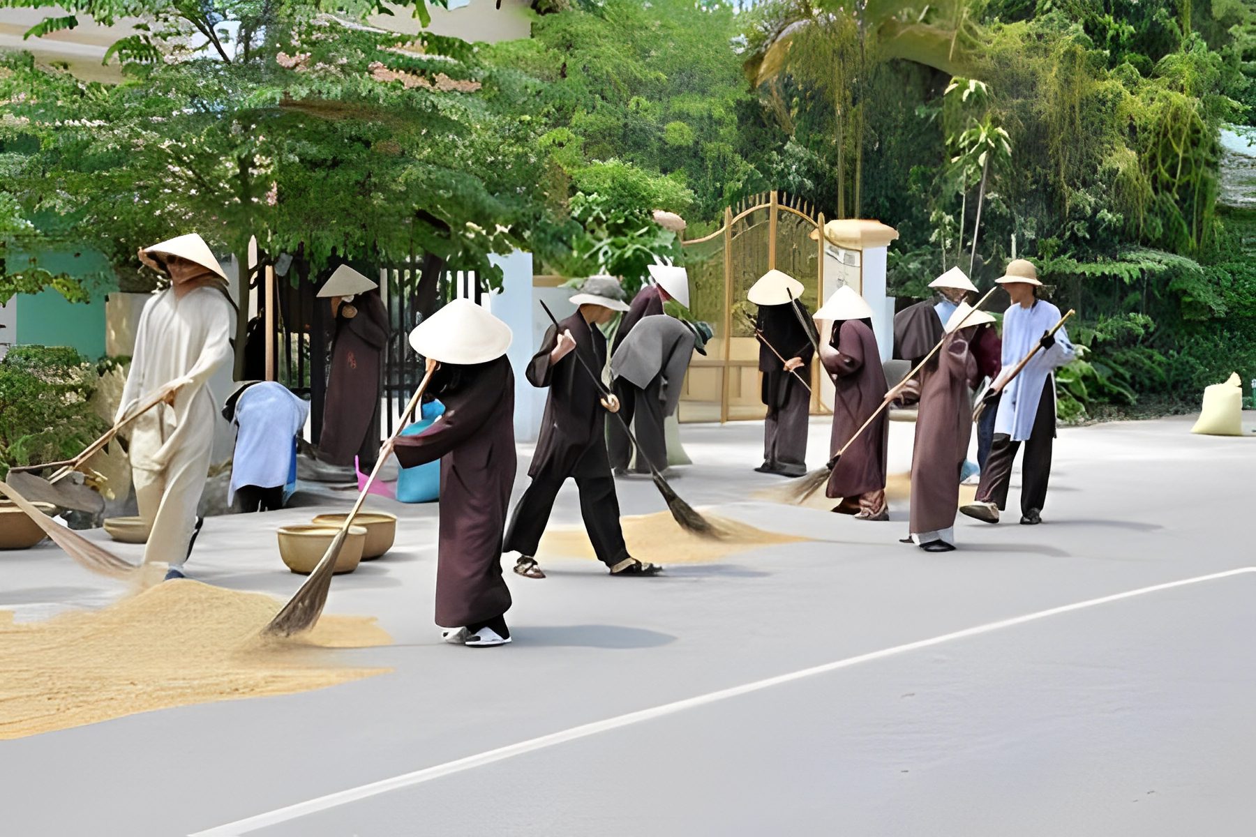 People sweeping outdoors with traditional brooms.