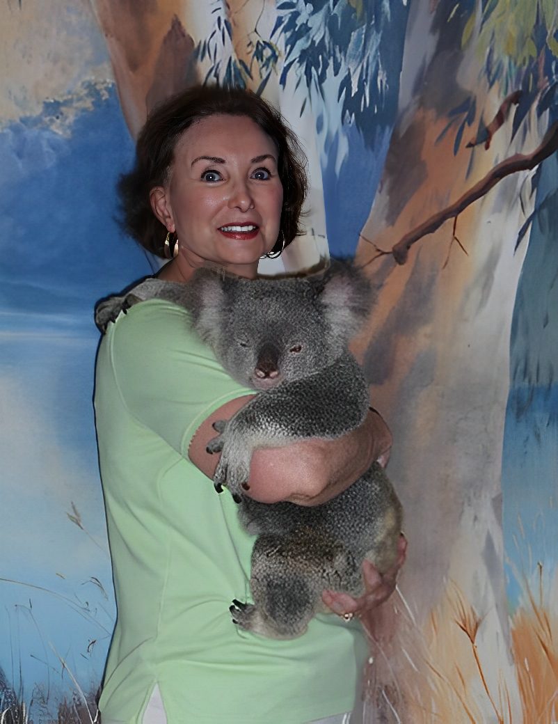 Woman holding a koala in front of mural.